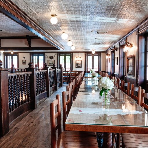 Upstairs balcony of Goode Co. restaurant with long glass top table, chairs, and white flowers at each setting.