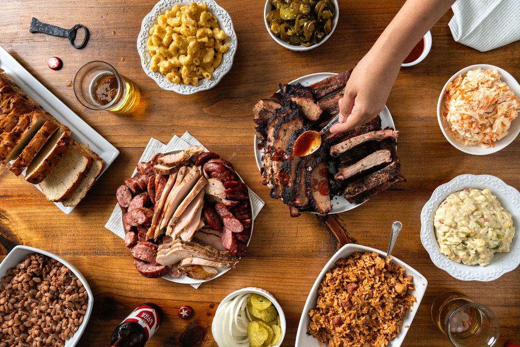 BBQ party pack featuring sliced turkey, sausage, brisket, beans, coleslaw and potato salad.